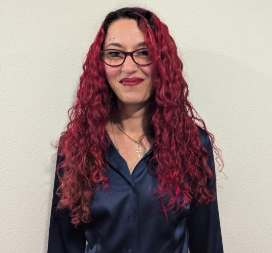 Foto Daphne, rood haar, draagt een bril, blauw bloesje.