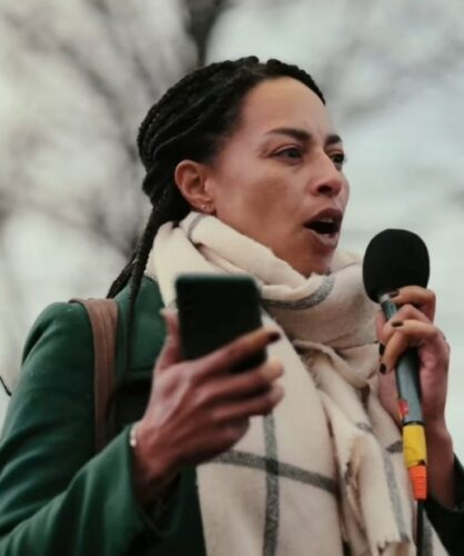 Patricia met een microfoon in haar hand al speechend op een demonstratie
